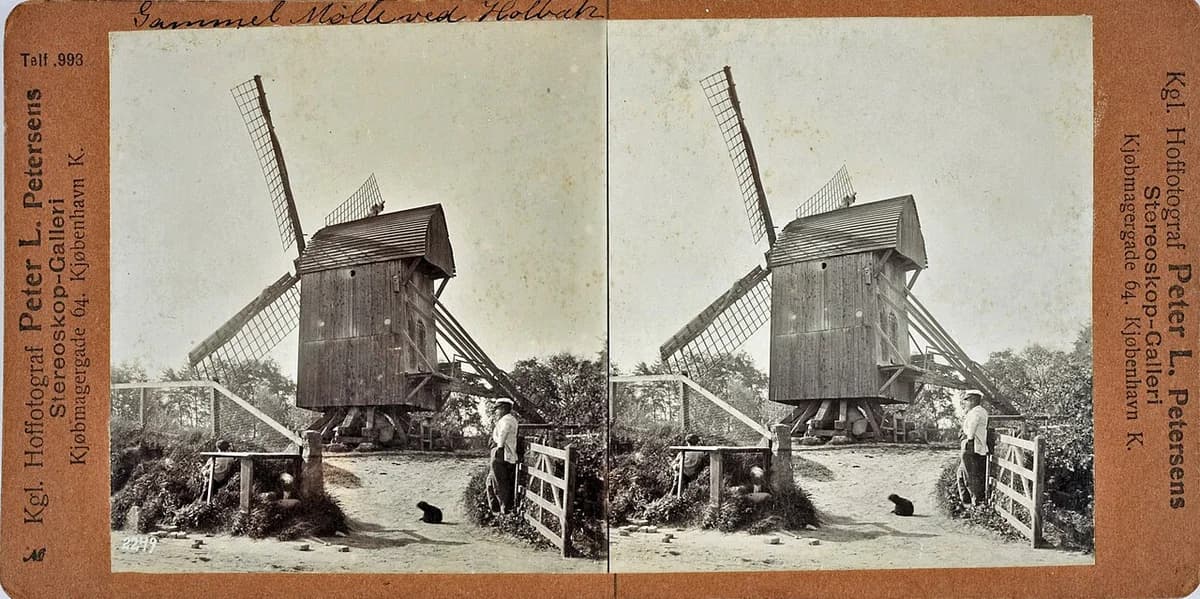 Stereoscopic photo of a wooden windmill in Holbæk with a man standing nearby.
