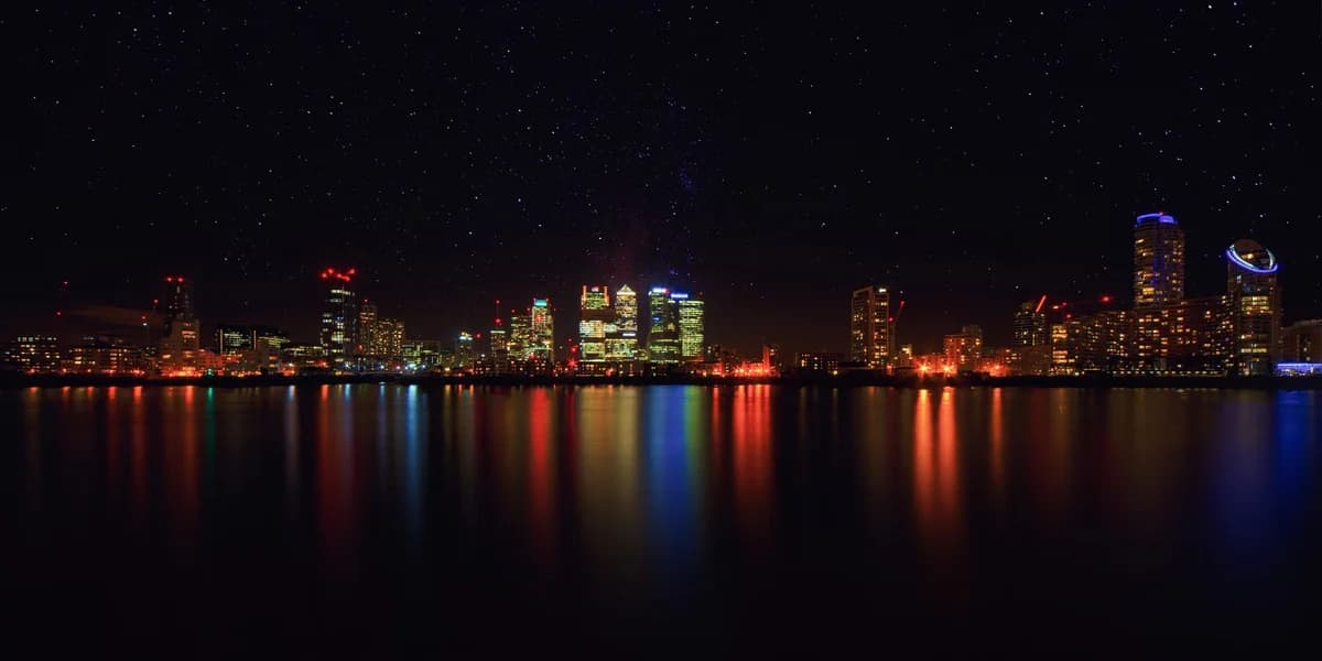 Night city skyline reflected on water under a starry sky